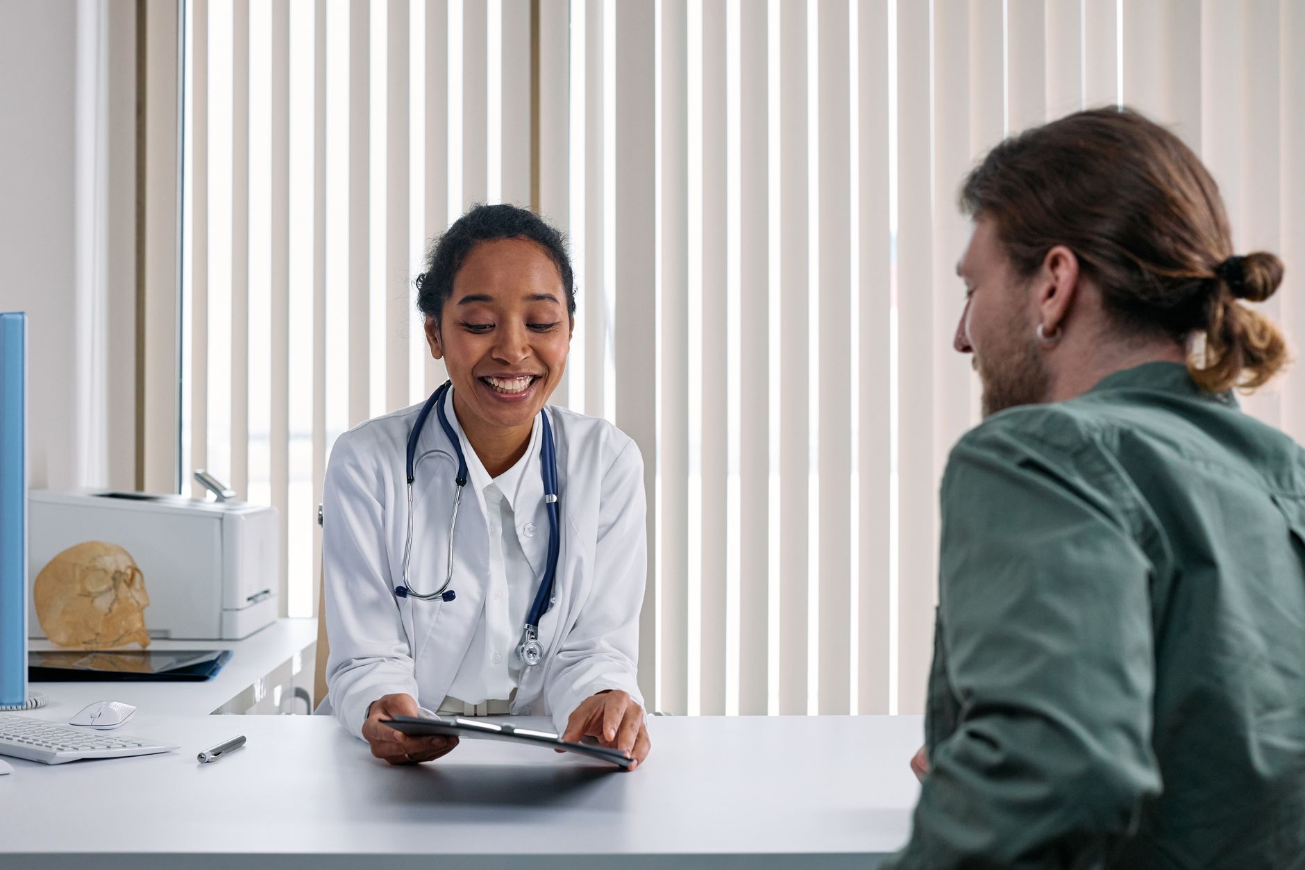 A smiling doctor talking with a patient across her desk